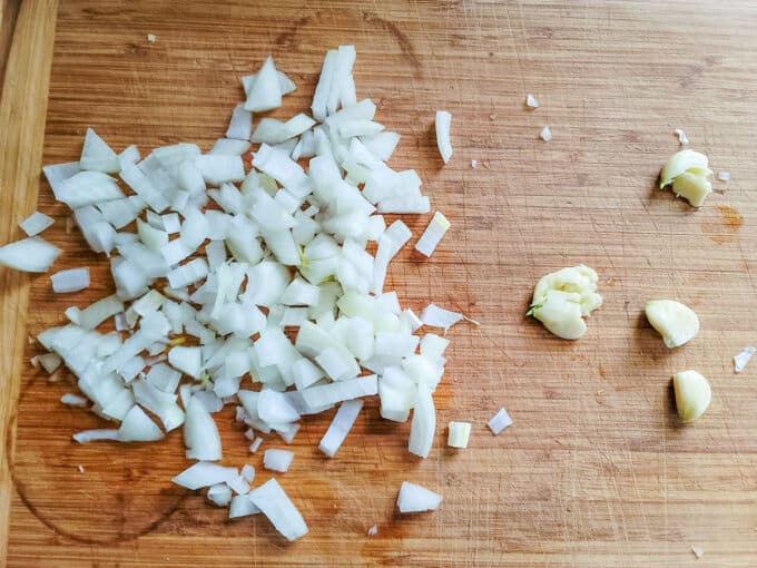 Chopped onion and garlic on cutting board.