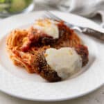 Two pieces of venison Parmesan on a bed of spaghetti.