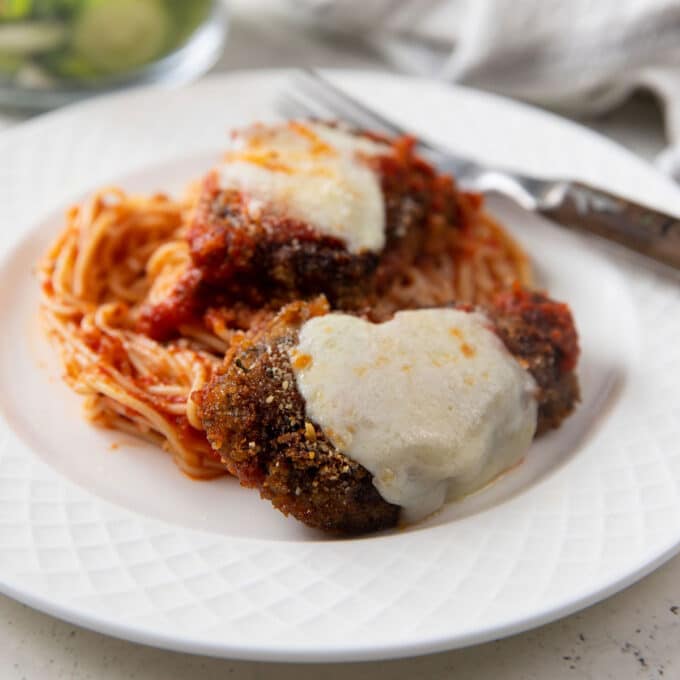 Two pieces of venison Parmesan on a bed of spaghetti.
