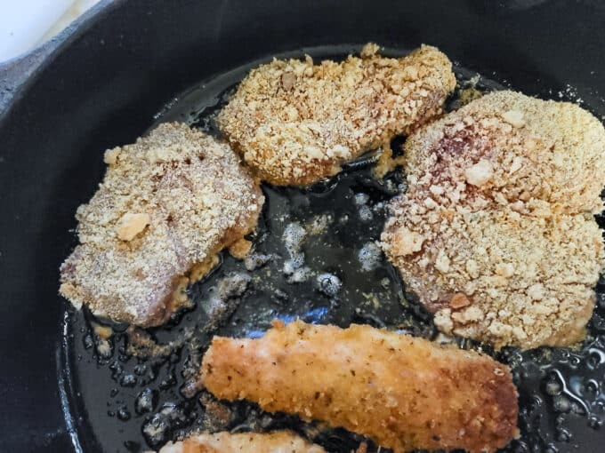 Breaded loins added to cast iron pan with oil.