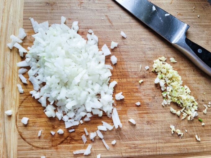 Chopped onion and garlic on cutting board.