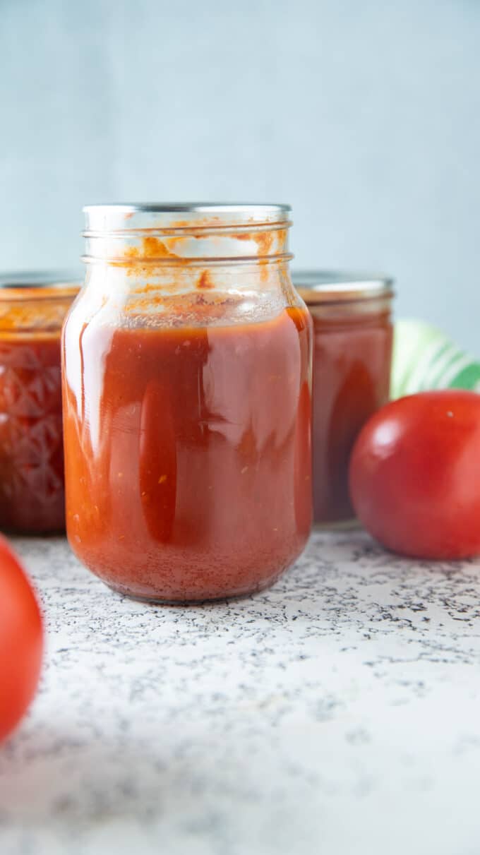 Pint jar of tomato ketchup on a white board.