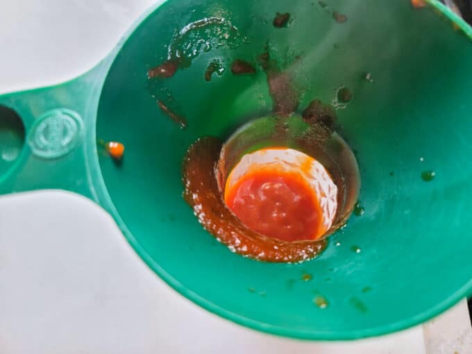 Adding ketchup to jar with canning funnel.