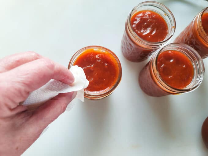 Wiping the rims of the jar to clean it.