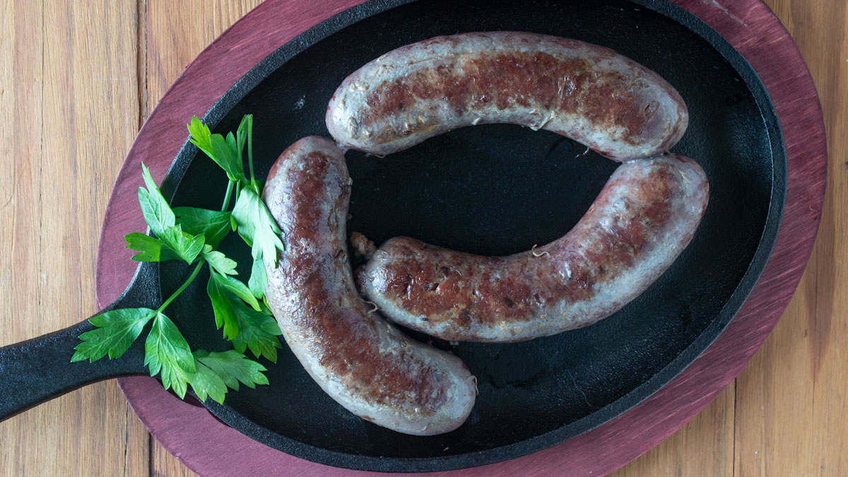 Overhead shot of goose sausage in a cast iron pan. 