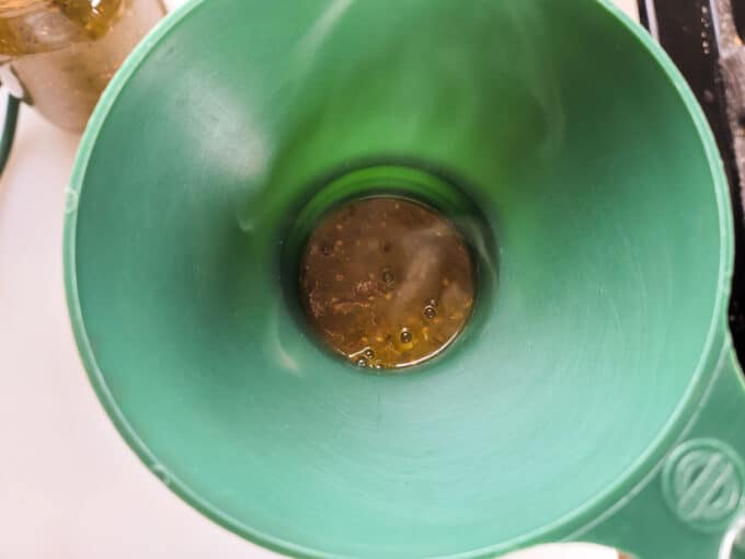 Sauce added to jar with the aid of a canning funnel.