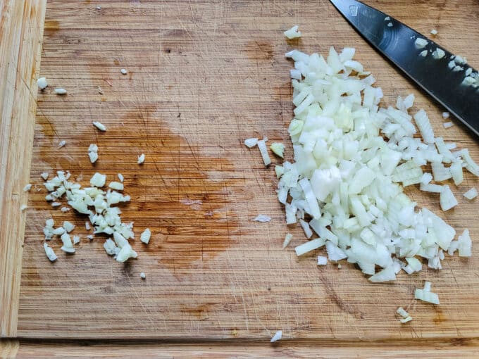 Chopped onion and garlic on a cutting board.