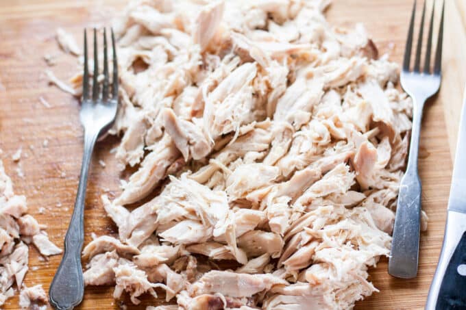 Pulled chicken on cutting board.