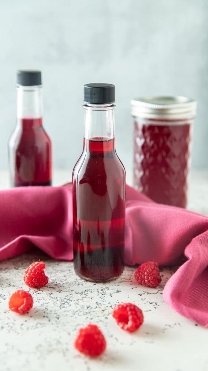 Bottles and jars of colorful raspberry vinegar.