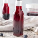 Bottles of blackberry syrup with fresh berries.