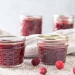 Jar of cranberry butter on white background.