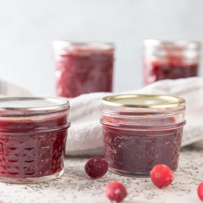 Jar of cranberry butter on white background.
