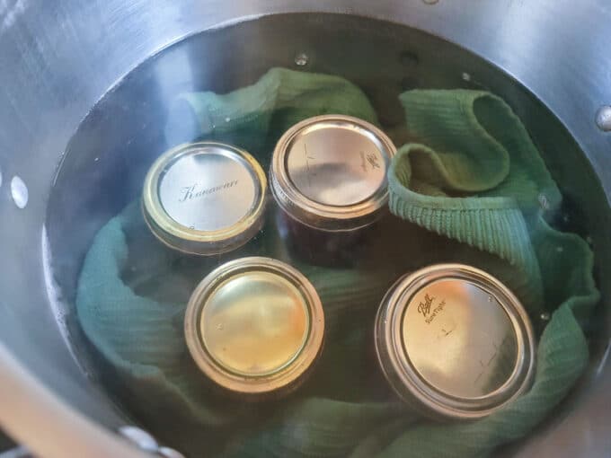 Jars added to added to a pot with a blue towel in it to protect the bottom of the jars.