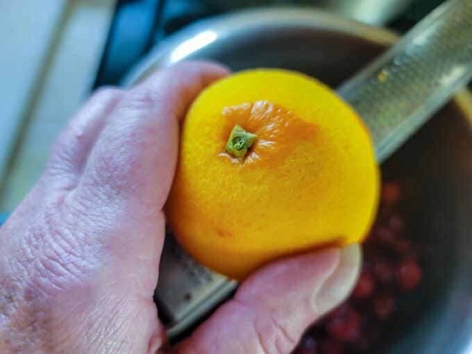 Grating orange zest into the pot.