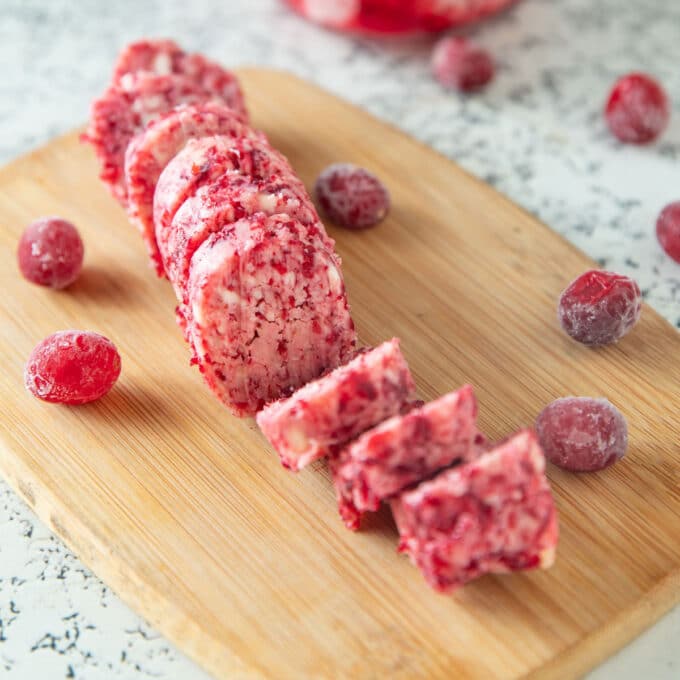 Sliced cranberry butter on a wooden cutting board.