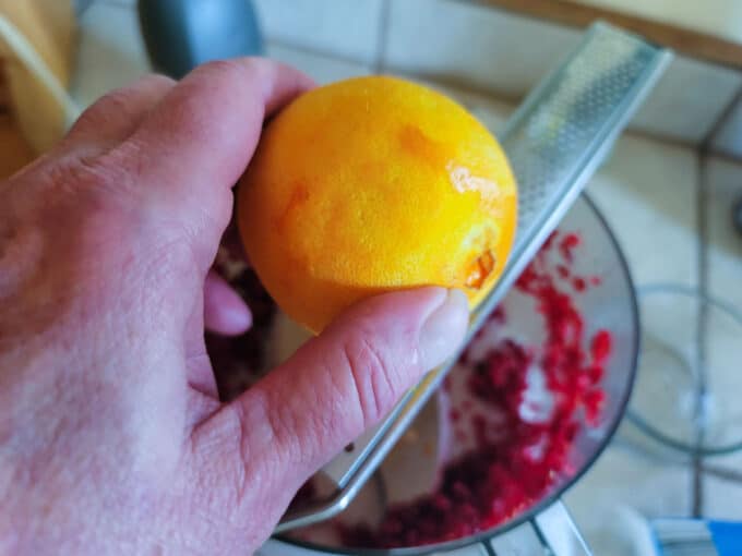 Grating orange zest into bowl.