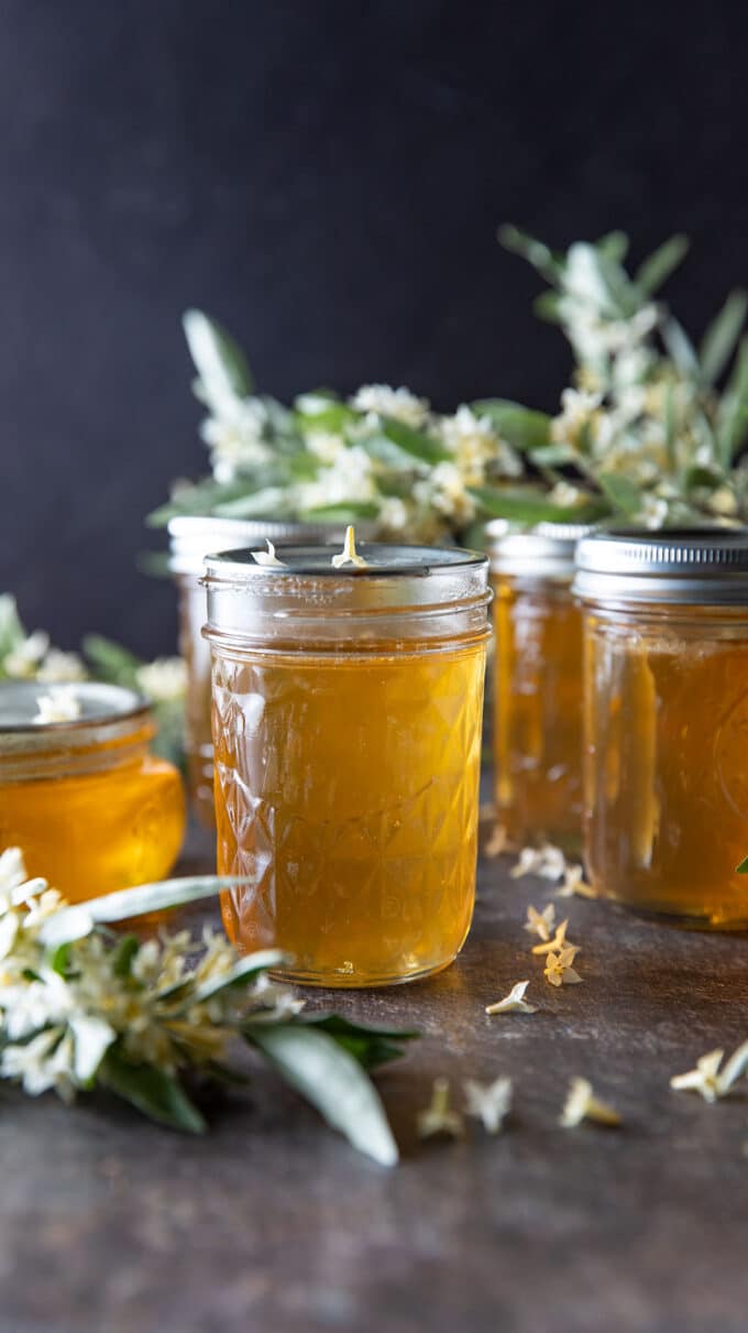 Jars of jelly with flowers in the background. 