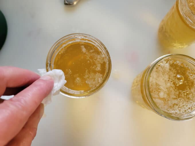 Wiping off the rims of the jar with a paper towel.