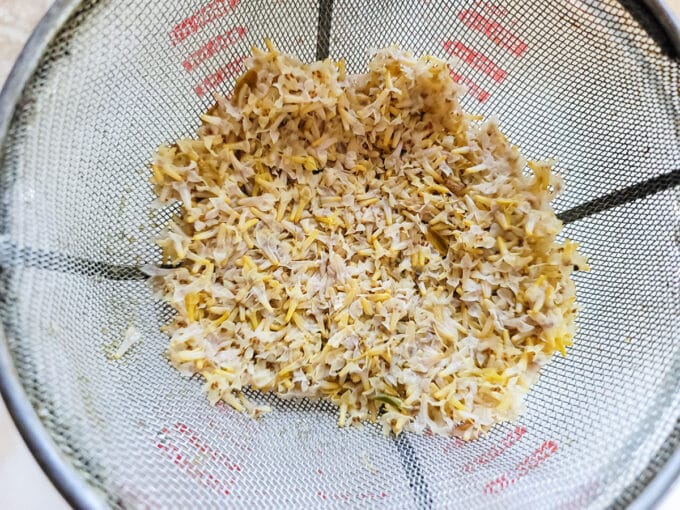 Straining the petals out of the tea with a strainer.