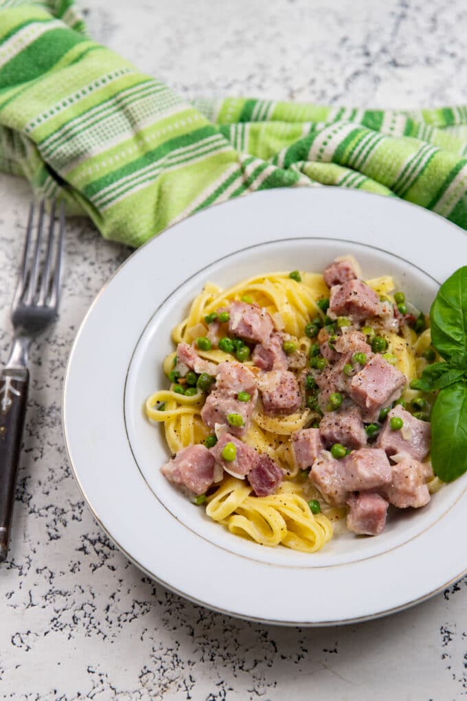 Bowl of creamy pasta on white board. 