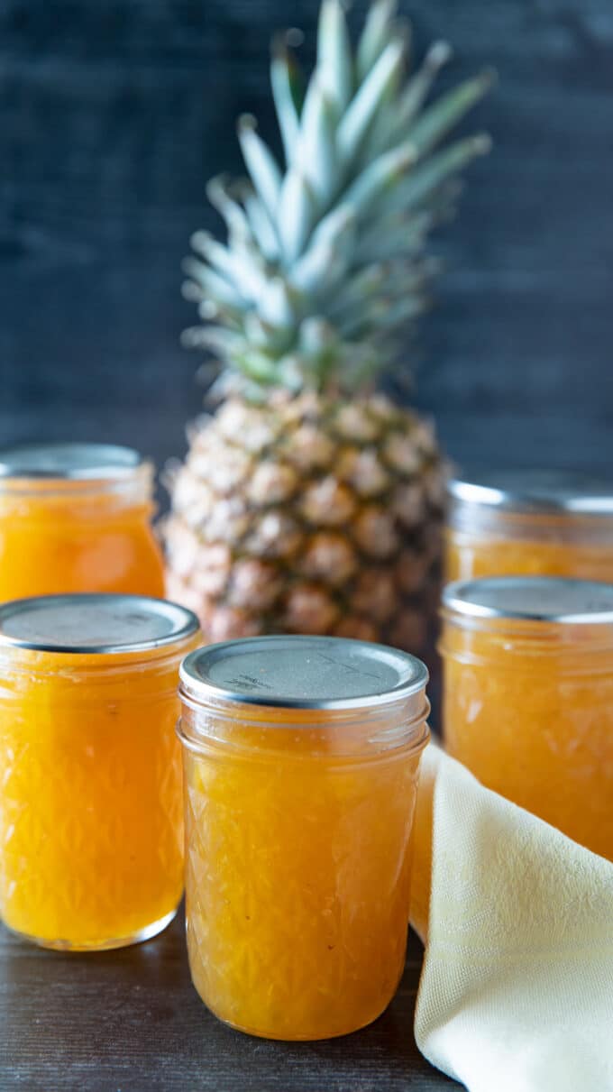 Jars of pineapple jelly with a whole pineapple.