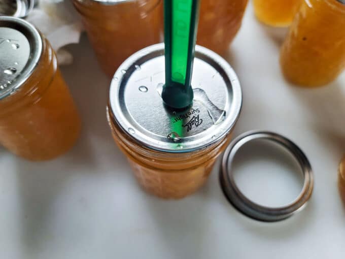 Adding lid to the jar with a lid lifter.
