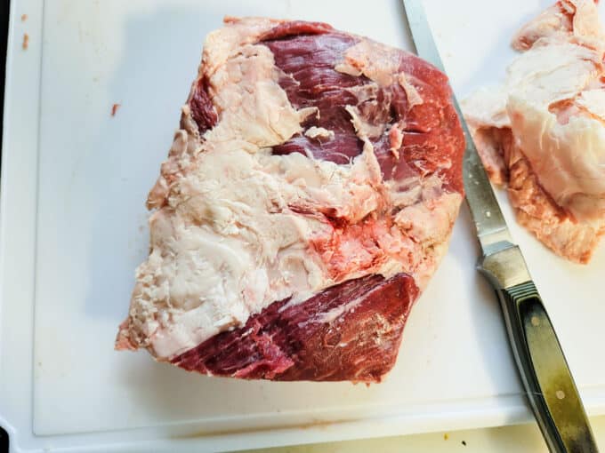 Trimming the fat off of the top side of the meat.