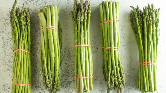 Bundles of fresh asparagus on a white board.