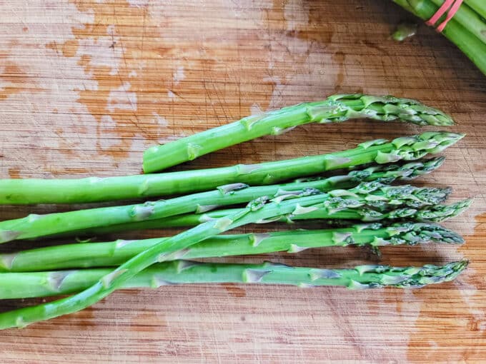 Cut asparagus on a board, measuring other spears.