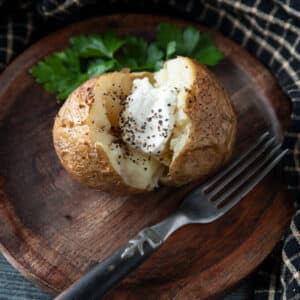 Split baked potato topped with sour cream and pepper.