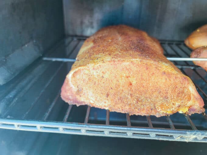 Pork roast in smoker with temperature probe placed in the center.
