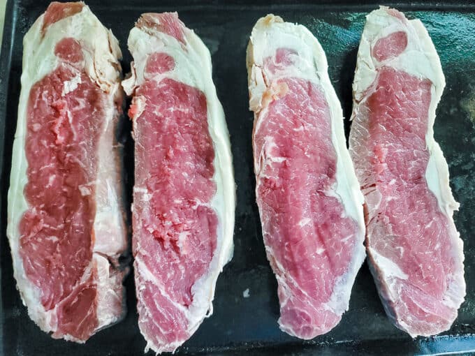 Sliced steaks on antique baking sheet.