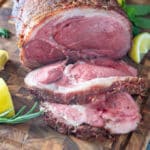 Sliced leg of lamb on wooden board.