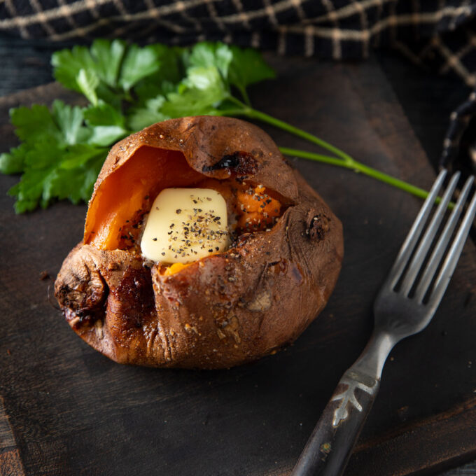 Opened sweet potato with a pat of butter inside.