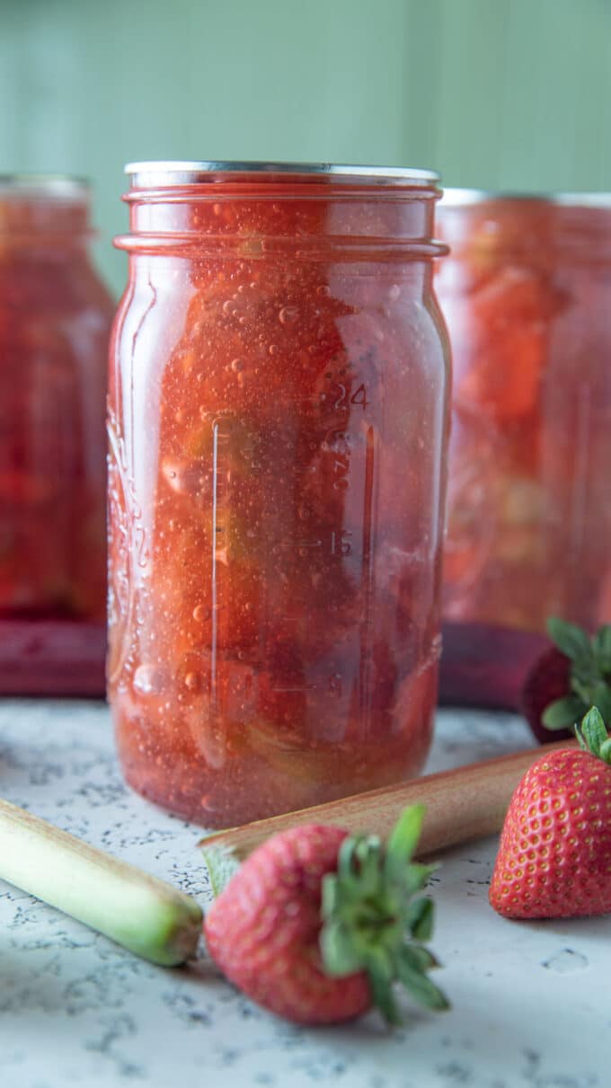 Jars of pie filling with fresh fruit next to them.