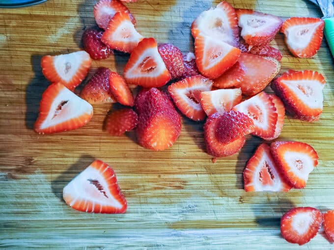 Sliced strawberries on a cutting board.