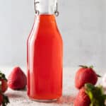 Bottle of strawberry vinegar with fresh strawberries.