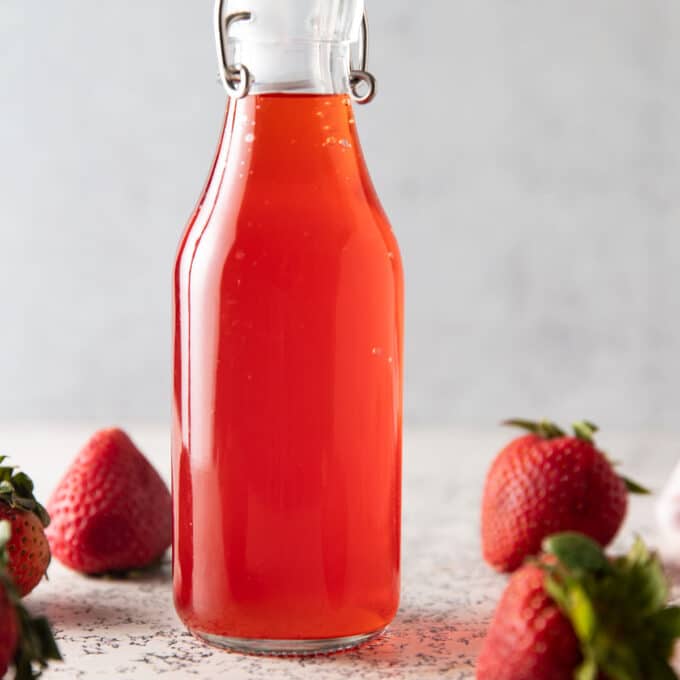 Bottle of strawberry vinegar with fresh strawberries.