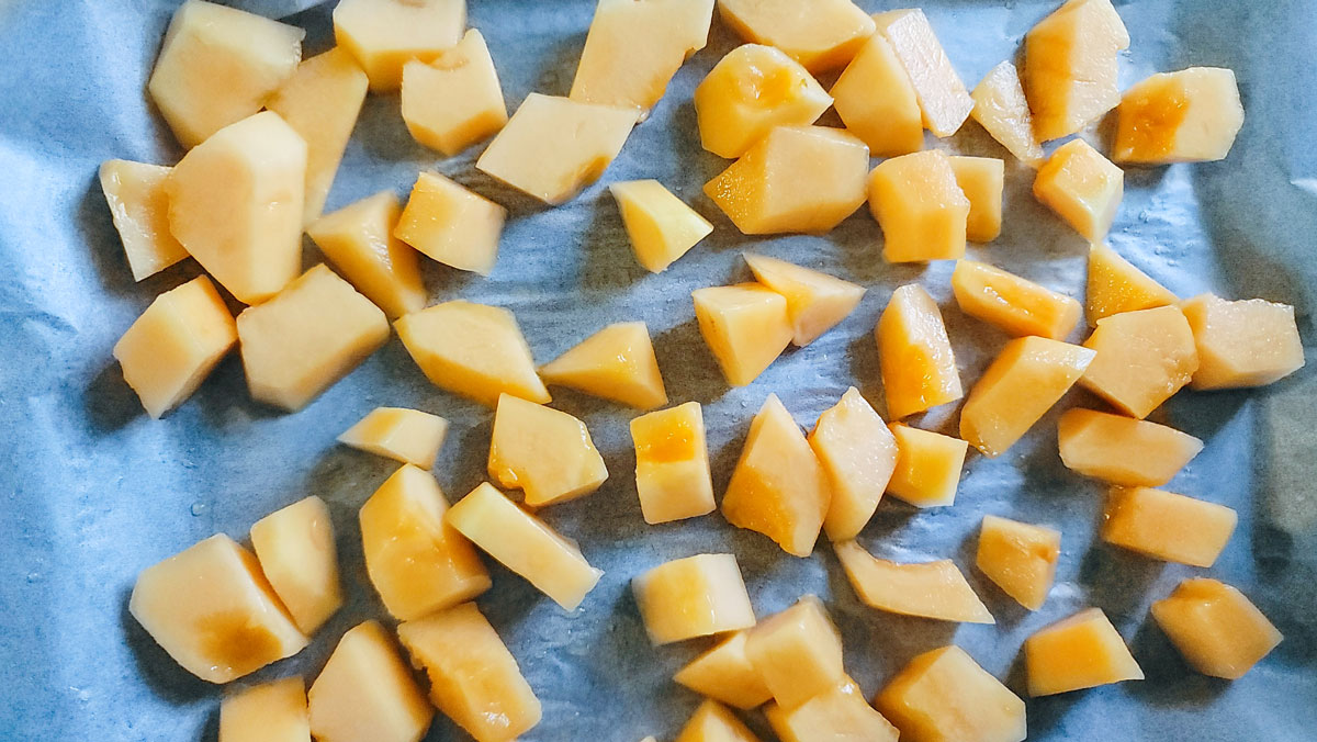 Parchment lined baking sheet with cantaloupe lined up.
