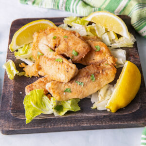 Pile of fried crappie on a wooden plate.