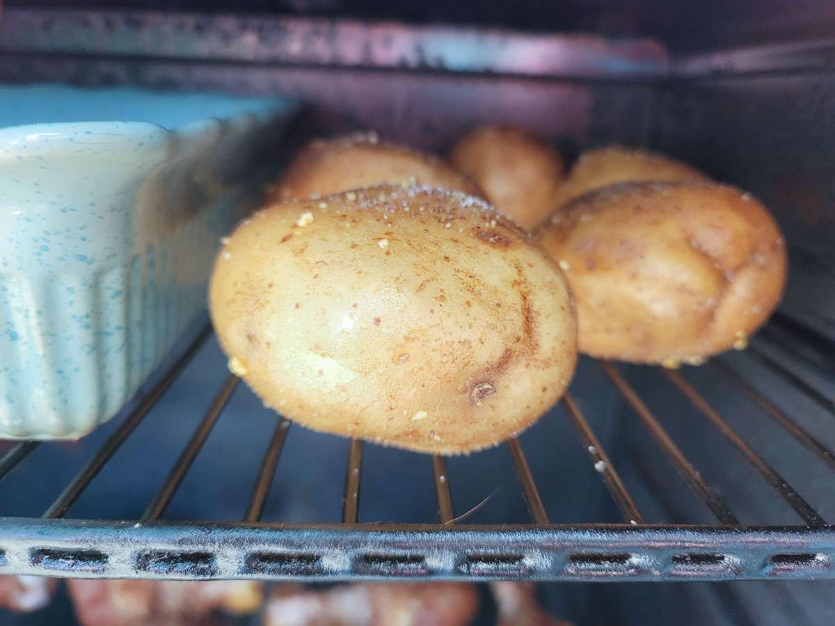 Whole potatoes in a smoker on the racks.