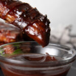 Dipping smoked shotgun shell in BBQ sauce.