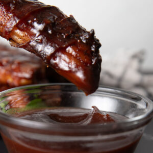 Dipping smoked shotgun shell in BBQ sauce.