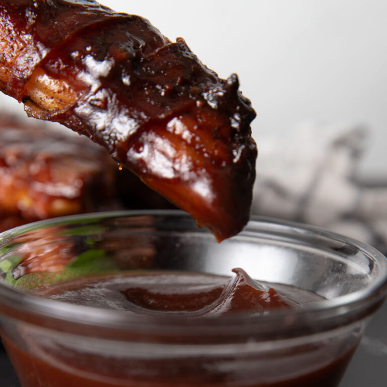 Dipping smoked shotgun shell in BBQ sauce.