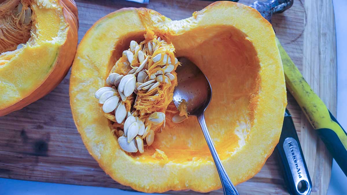 Pumpkin cut in half, scraping out the seeds.