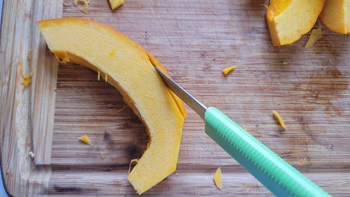Cutting off the rind off of a slice of pumpkin.