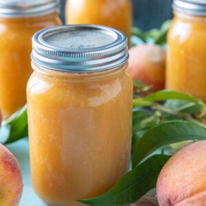 Jars of peach juice on a blue background.