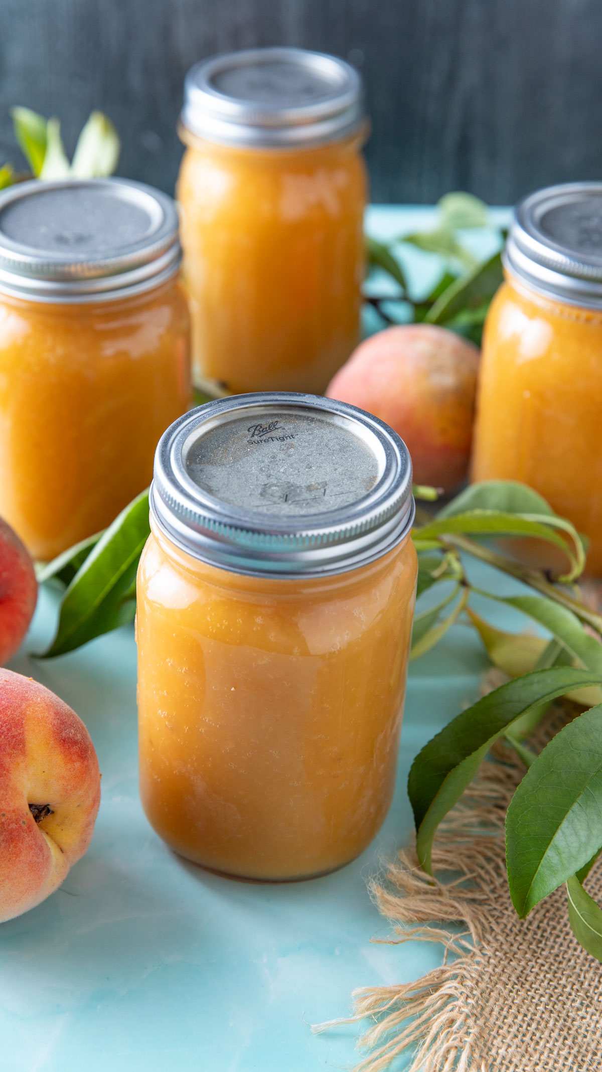 Jars of canned peach juice on a blue board.