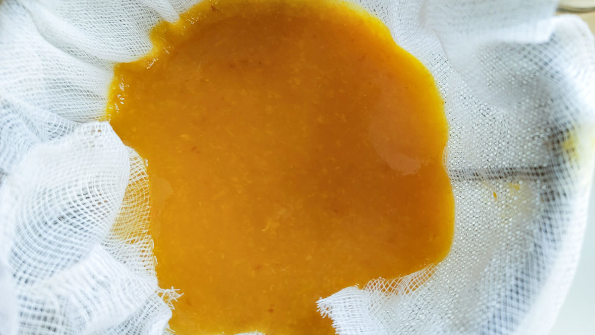 Straining peach juice through a cheesecloth sieve.