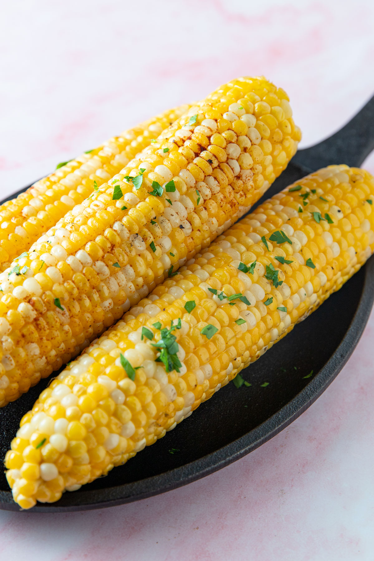 Smoked corn piled on a cast iron pan.